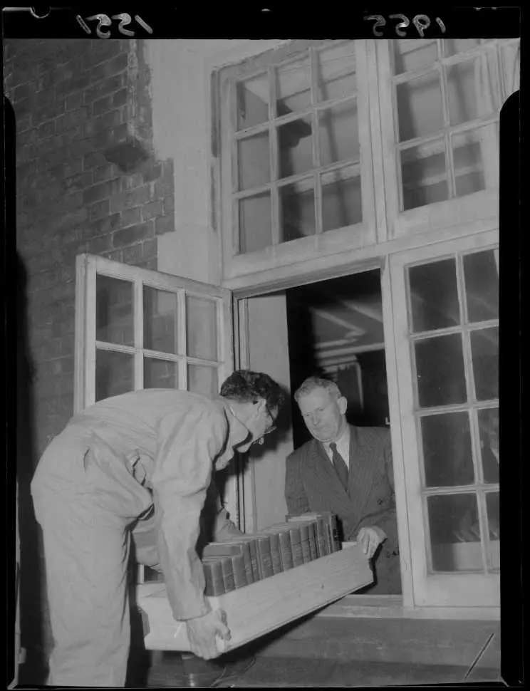 Staff of the Alexander Turnbull Library moving the book collection out a window.