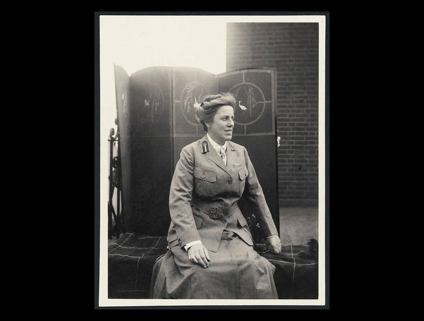 Black and white staged photo of Dr Agnes Bennett in army uniform and sitting in front of a decorated screen.