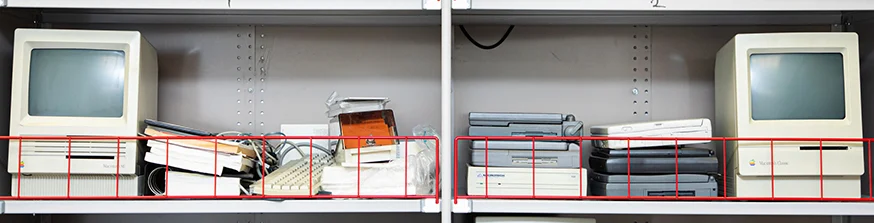 Old computer hardware and manuals on a shelf.