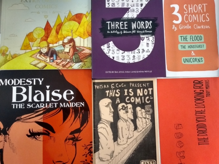 Collage of different comic covers all laid together on a table top.
