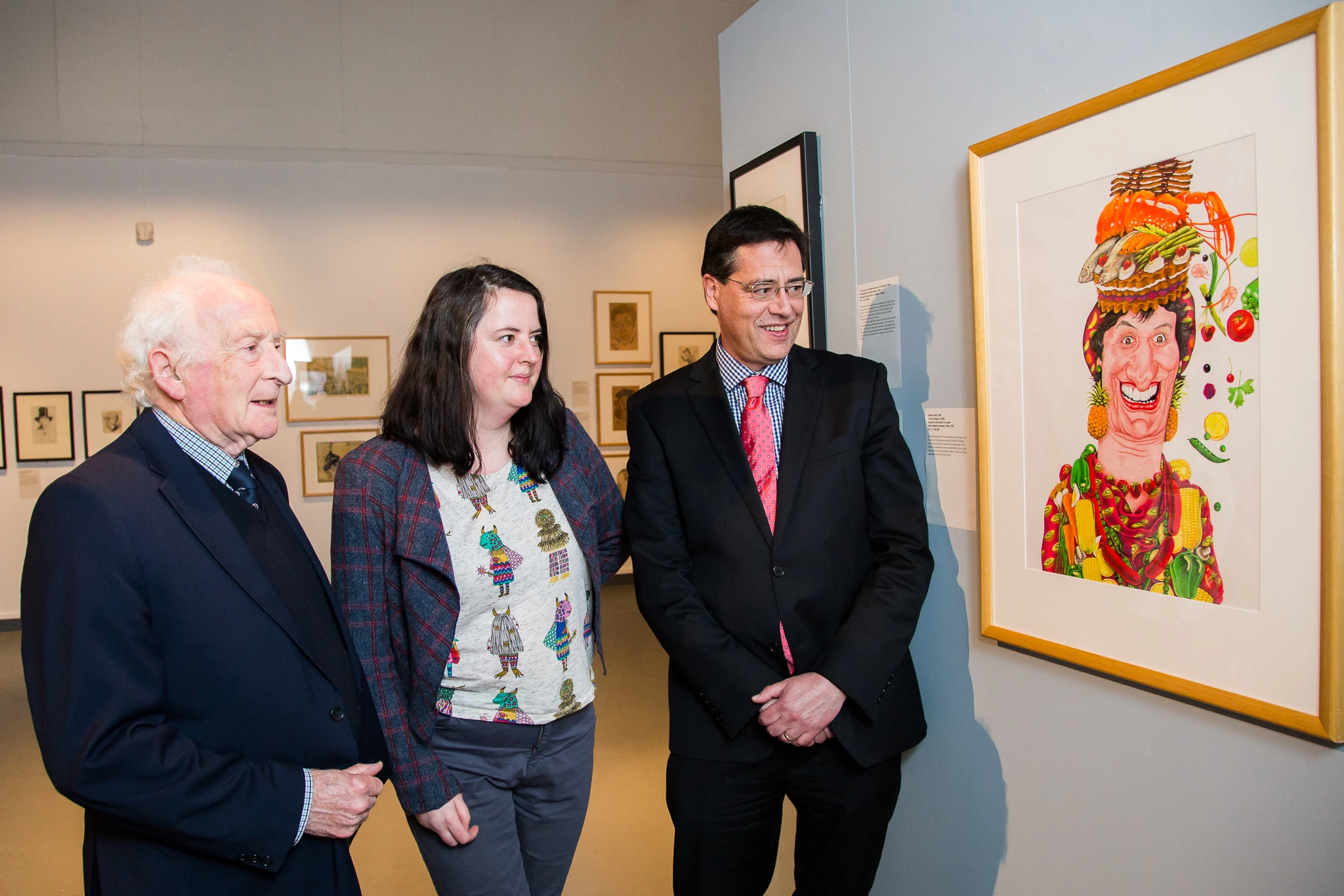 Ian Grant, Hannah Benbow and Oliver Stead standing in front of a framed caricature of Helen Clark.