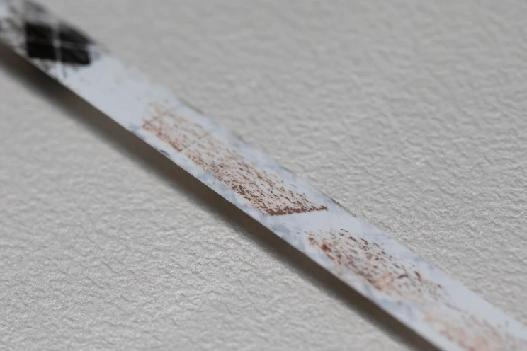 White leader tape with brown residue stuck to it, which is part of the magnetic layer from adjacent tape.