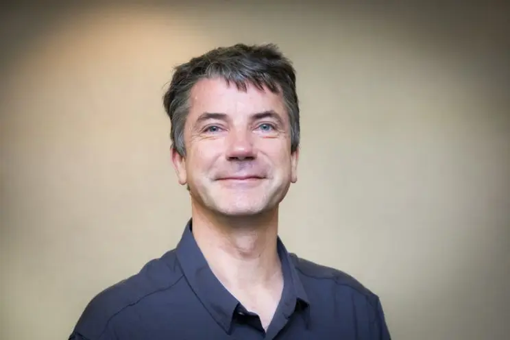 Portrait of a smiling man wearing a blue, collared shirt. 