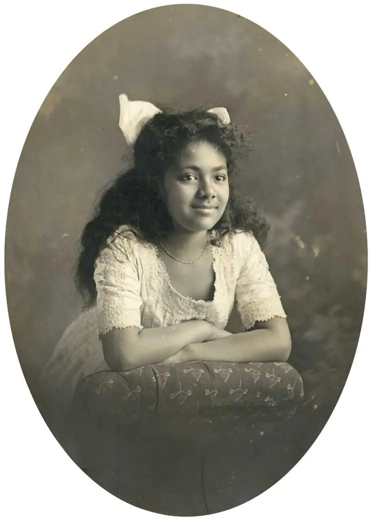 A black and white portrait of a young girl with a white ribbon in her hair. 