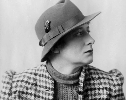 Black and white portrait of a woman wearing felt hat and checkered jacket. 