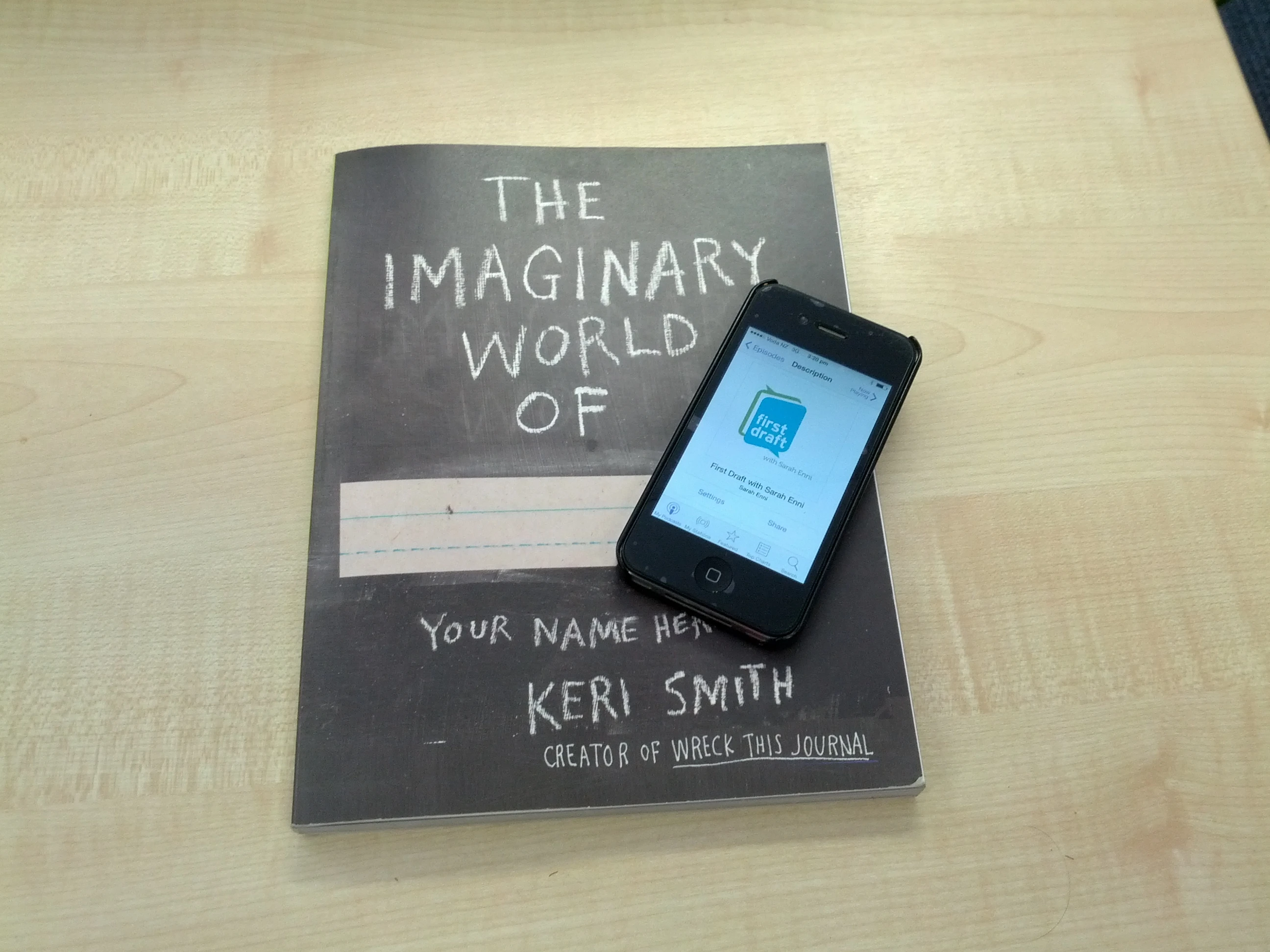 An Iphone on top of a book titled 'The imaginary world of'.