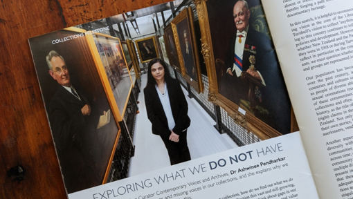 An open magazine with a picture and text visible, showing a woman standing among old, framed paintings. 