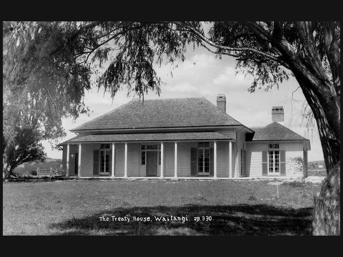 Black and white photo of the Treaty House at Waitangi, surrounded by trees.