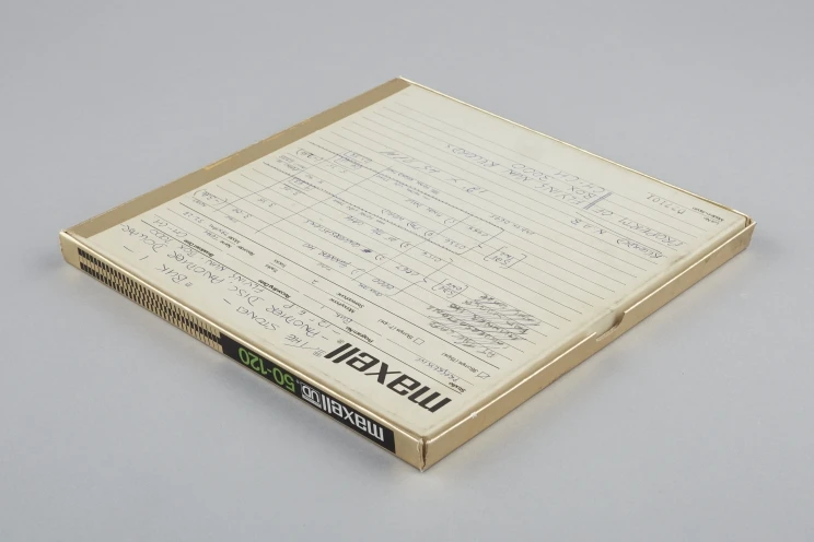 Back of box with magnetic tape, there is handwritten words and notes in blue and black ink.