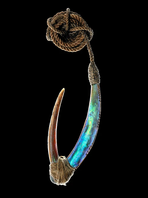 Colour photograph of a pā kahawai made of a paua shell shank and shell barb bound by muka fibre. See Description below.