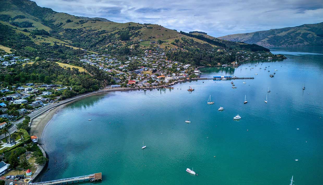 Photo showing a view of Akaroa overlooking the town, landscapes and harbour.