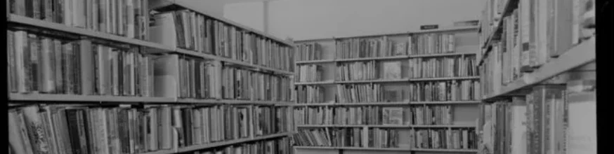 Black and white photo of library shelves  full of books. 