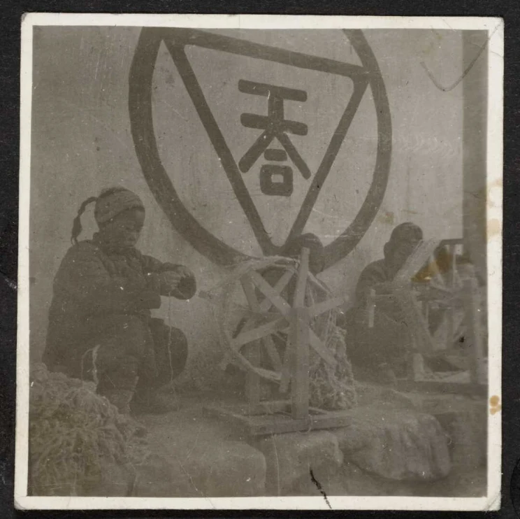 A faded photo shows a woman crouched on the ground next to a star-shaped wooden weaving wheel.
