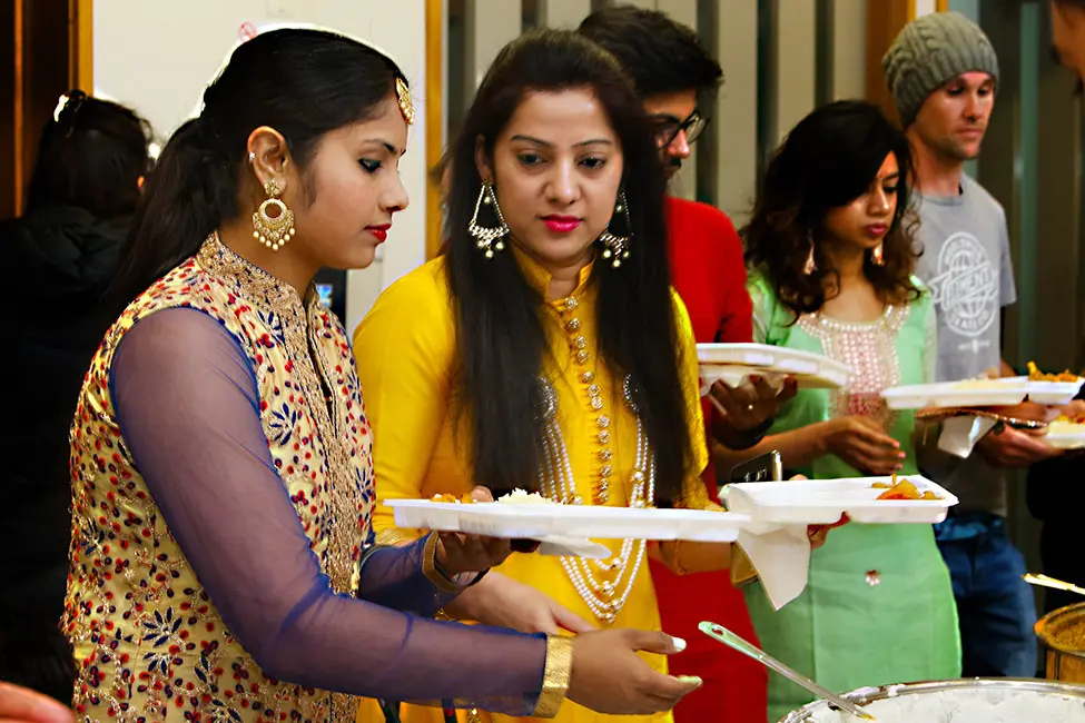 Colour photograph of people lining up for food at a Diwali festival. See Description below.