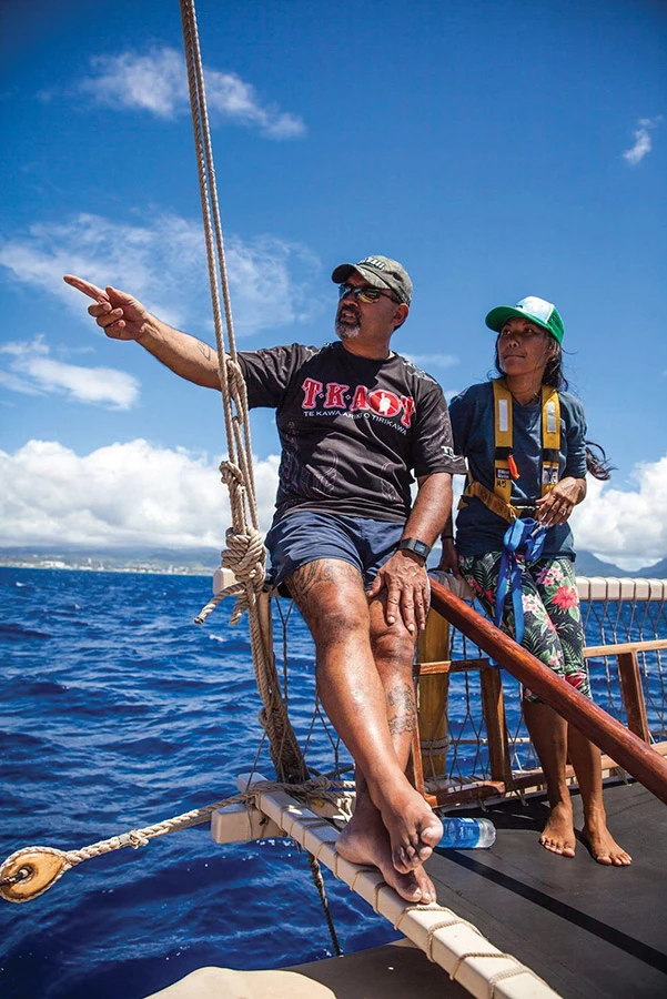 Colour photograph showing navigator Jack Thatcher teaching a student on board Ngāhiraka Mai Tawhiti on the ocean.