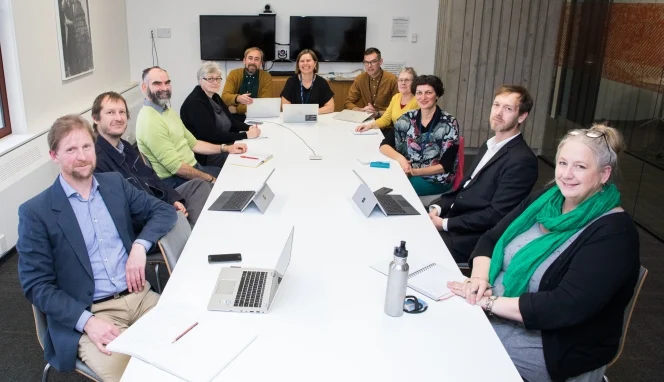 Shows staff from The Flying Nun Project working group sitting around a long white table.