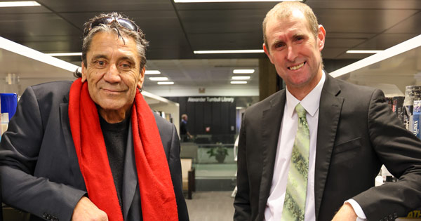 Inaugural Te Awhi Rito New Zealand Reading Ambassador Ben Brown with new ambassador Alan Dingley in a library.