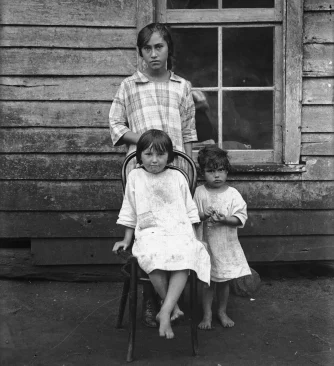 A woman with two children; one child is sitting on a chair.