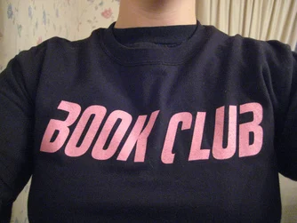 A girl wearing a black t-shirt the text 'Book Club' in bold pink font.