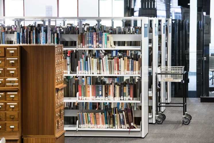 A view looking across the General reading room at shelves of books and wooden card catalogue.