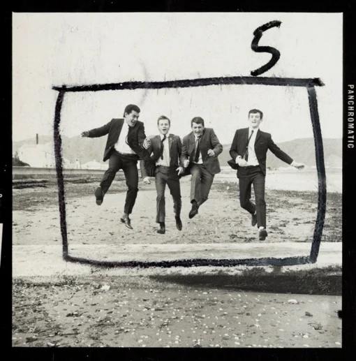 A black and white photo showing a group of four men all jumping in the air at once. There is a black, hand-written box around the men indicating possible crop lines. 