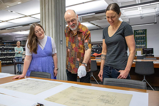 Three people looking at a manuscript. 