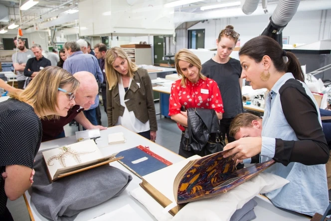 Laura Mirebeau, Conservator Books/Paper, demonstrating the potential digitisation challenges with a collection item that has tighter binding.