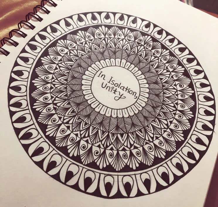 A hand-drawn mandala in black ink on white paper surrounds the words 'In isolation, unity'.