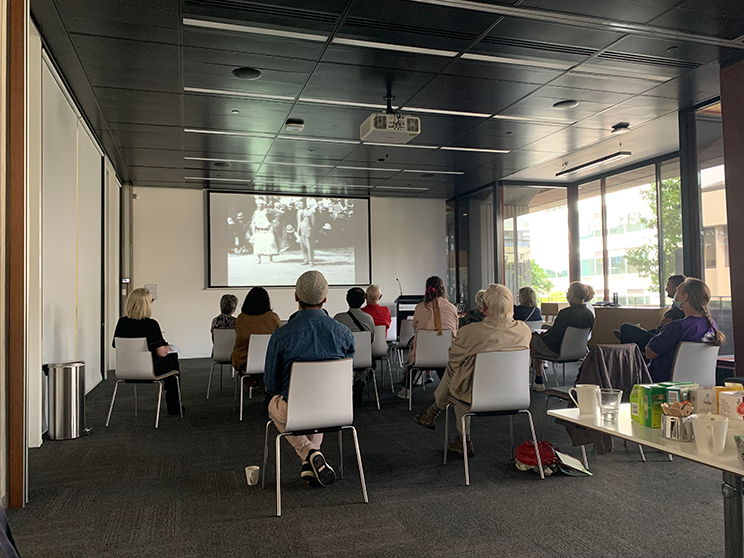 People in a room watching film footage. 