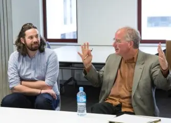 Mark Crookston and Dave Sanderson listen to Brewster Kahle, who is gesturing widely.