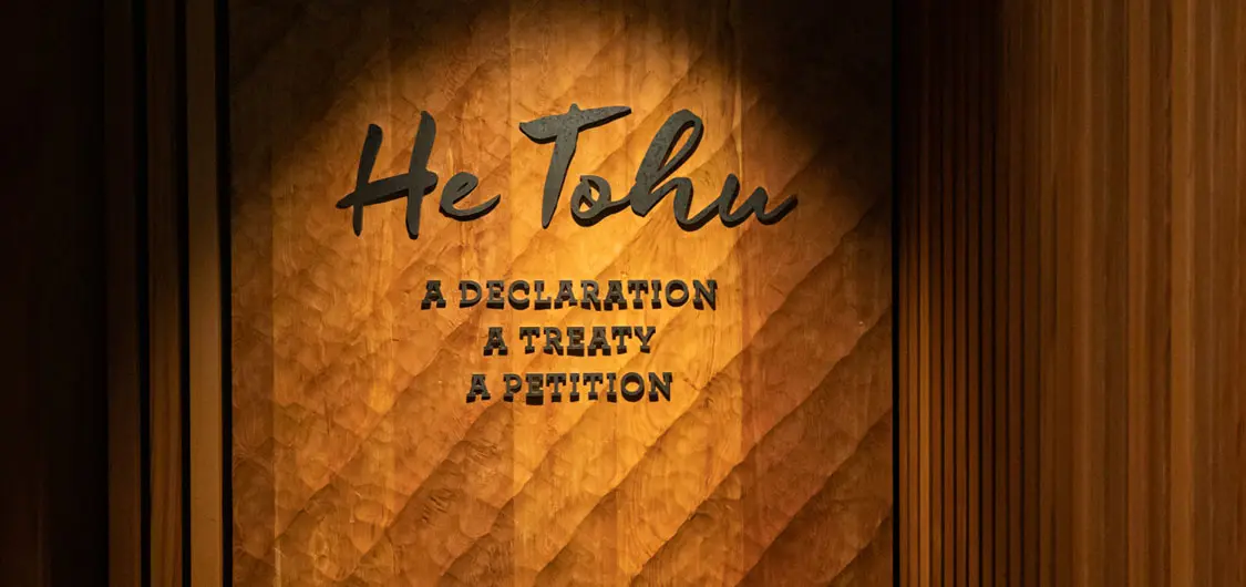 Beautiful curved wooded wall with sign on it He Tohu, a declaration, a treaty, a petition. 