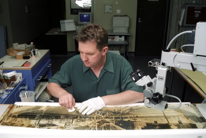 Conservator Mark Strange cleaning a flattened negative of the interior of Roach’s Department Store, Hastings.