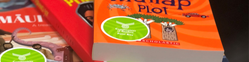Orange and red book covers with a sticker that says Communities of Readers Pūtoi Rito.