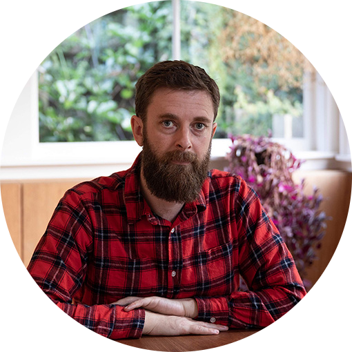 A man wearing a red check shirt sitting at a table.