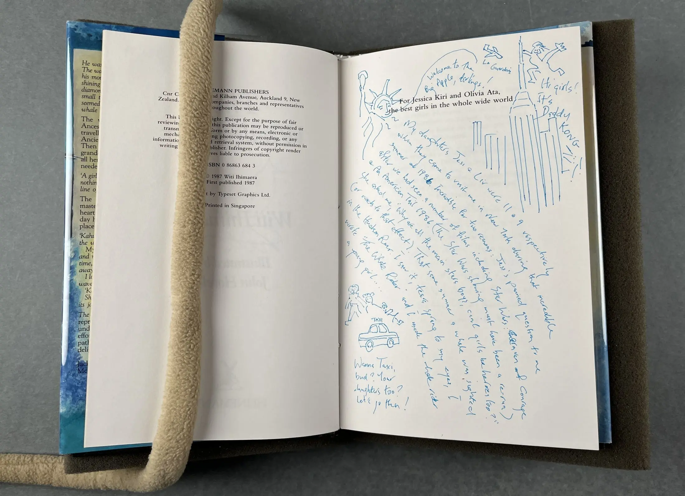 A book held open to show handwritten drawings and words on the dedication page. 