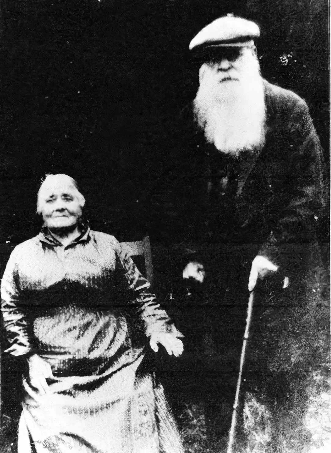 Black and white photo of Rora Orbell seated next to Arthur Orbell standing and holding a cane.