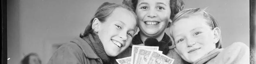 Three girls holding a fan of dollar notes they have saved.