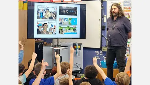 Toby Morris talking to a group of students with their hands raised.