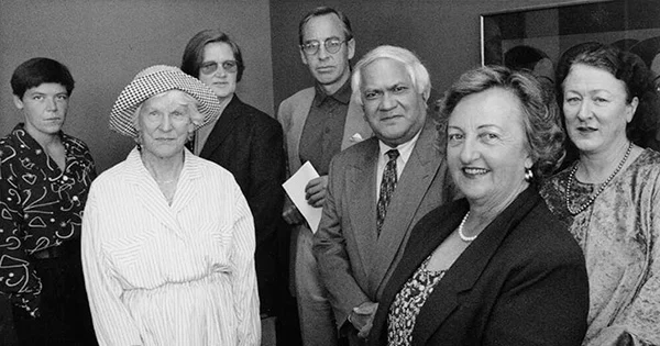 Black and white photo of 7 people wearing formal clothing, posing for the camera.