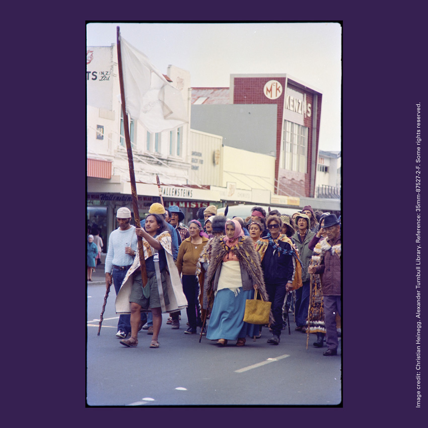 Front of curiosity card TMCC13 with an image of Tame Iti holding a pou whenua, accompanied by Whina Cooper leading the Maori Land March in Hamilton