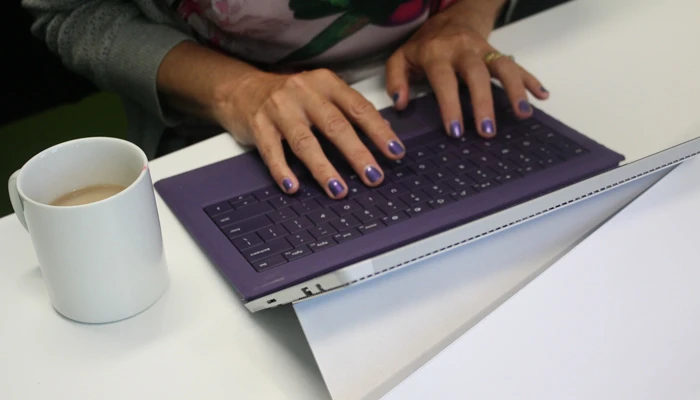Person wearing purple nail polish typing on a purple keyboard
