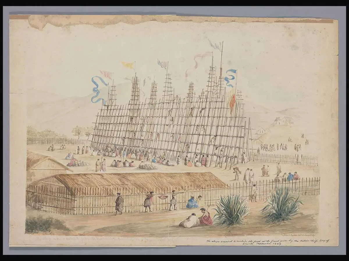 Watercolour painting of an enormous hākari (feast) displayed on an open, wooden structure, with flags flying from poles on top and people climbing up its sides. 2 low whare are nearby and a fence encloses the hākari and buildings.