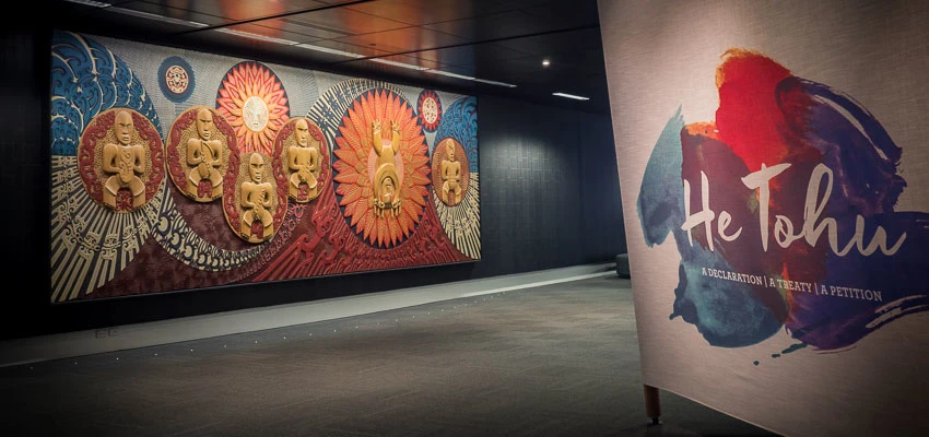 Entrance to the He Tohu exhibition showing Te wehenga o Rangi rāua ko Papa by Cliff Whiting and a He Tohu exhibition banner.