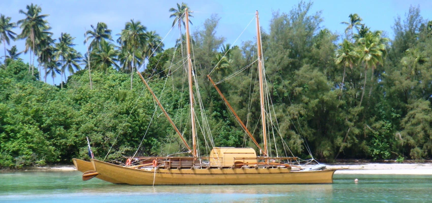 Large traditional double-hulled vaka in Rarotonga moored with sails let down