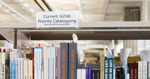 Bookshelf with a note on it saying "Current NZNB priority cataloguing"