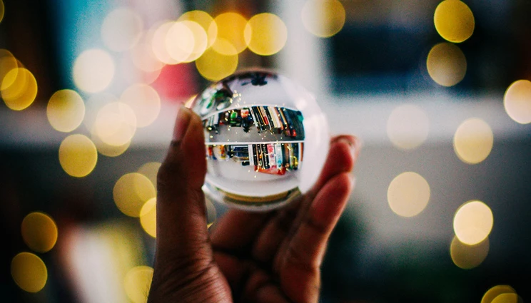 Hand holding a Christmas decoration globe reflecting books.