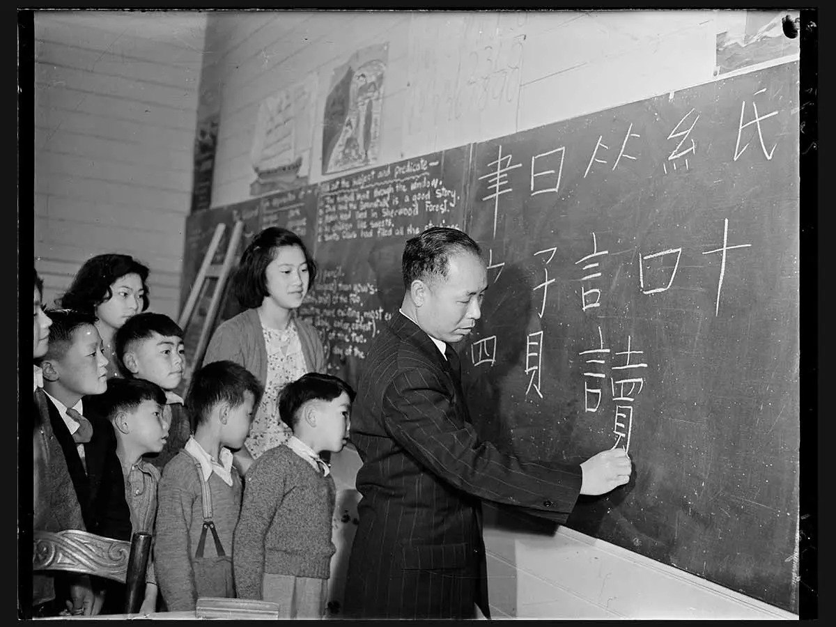 8 children and a teacher at a blackboard during lessons to teach the children to write Chinese.