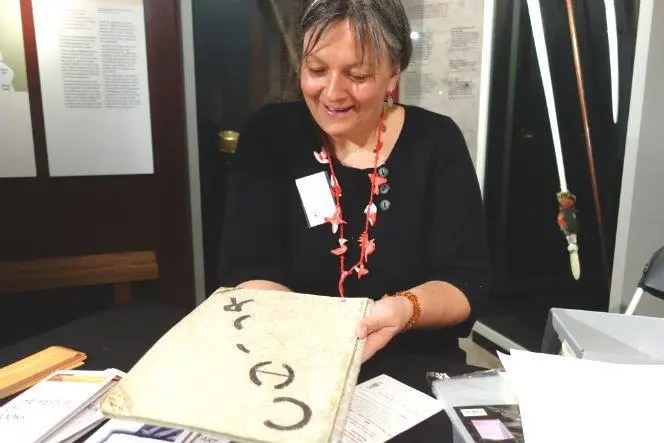 A woman smiles as she handles an old and precious-looking document
