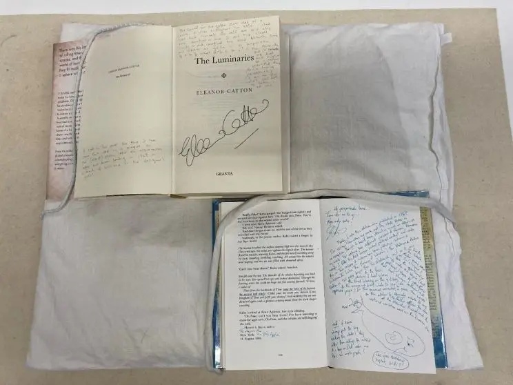 Two copies of annotated books are arranged on a table with pages open to different examples of hand-written annotations. 