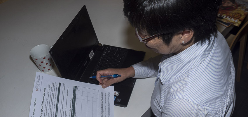 Person with a laptop reading a loan requirement form.